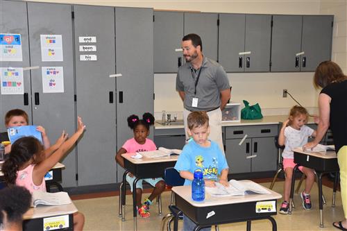 Tim Holtcamp calling on girl raising her hands in classroom to talk with him